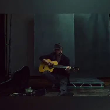 Cinematic studio portrait of man in burgundy shirt playing acoustic guitar with dramatic teal-green moody lighting, photo by 312 Elements Headshot Photography, Chicago, IL portrait photographer