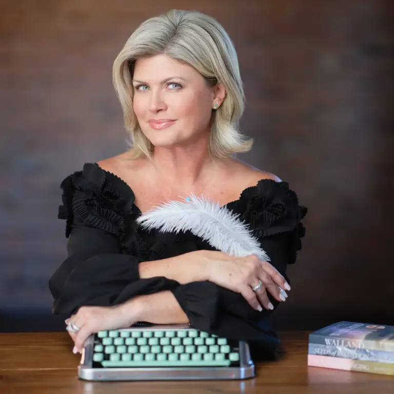 Andrea Thome in black off-shoulder top at wooden desk with typewriter, professional headshot by 312 Elements, headshot photographer 312 Elements Headshot Photography | Chicago, IL
