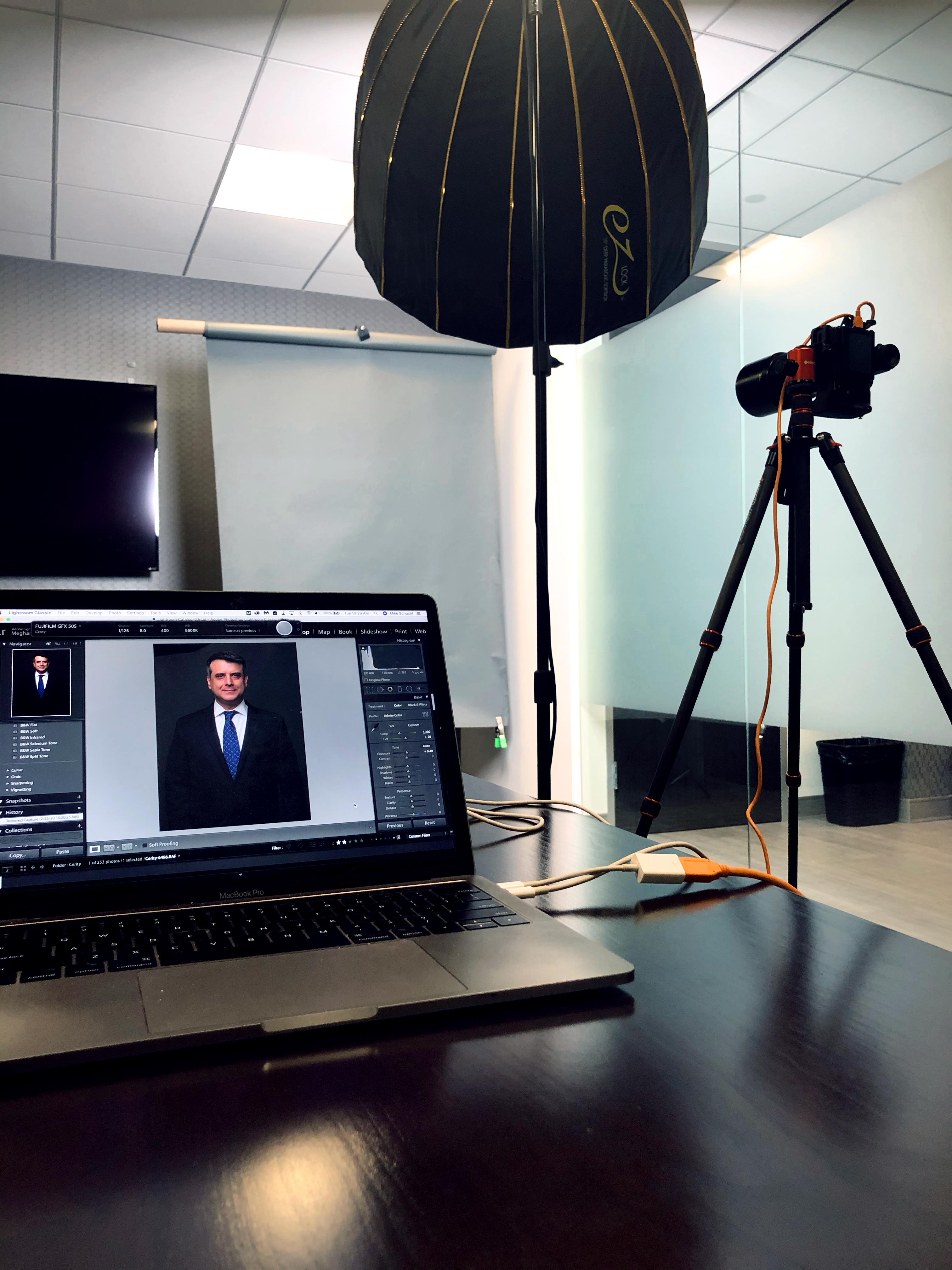 Image of Photo Booth for headshots setup in an office featuring a camera on a tripod, a soft box on a light stand and a computer using capture one pro.