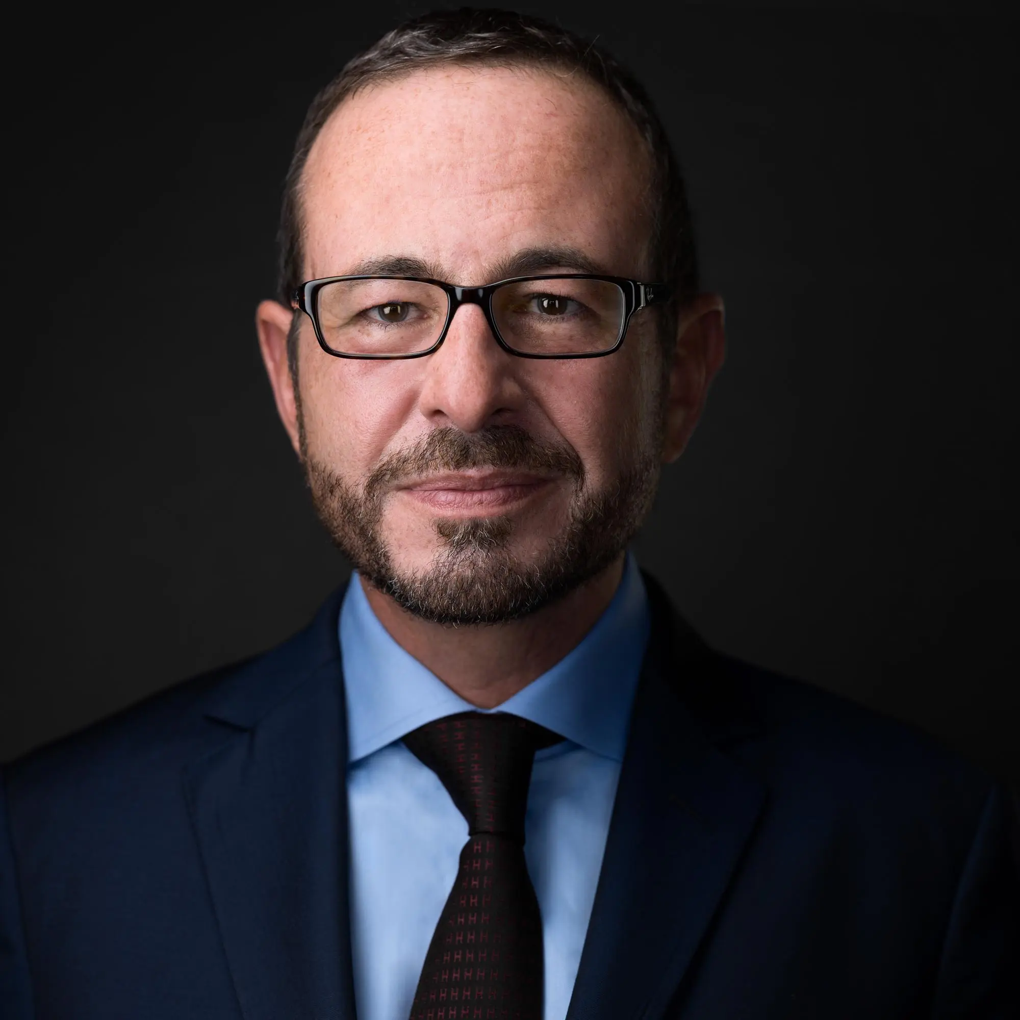 A business professional in a suit and tie benefiting from a high-quality headshot, emphasizing the significance of first impressions in a competitive market.