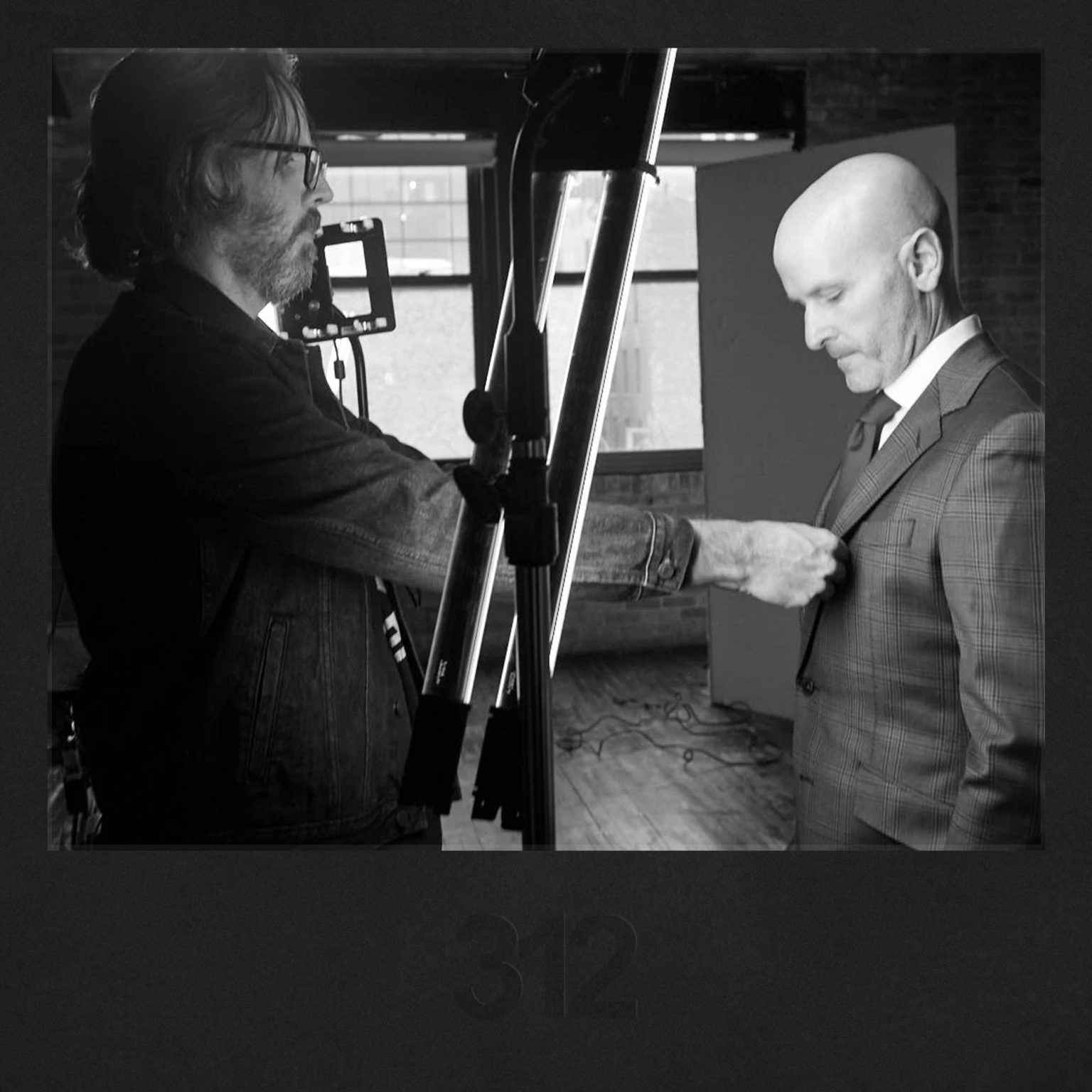 Photographer adjusting a client's suit during a professional headshot session, emphasizing the importance of attire for a polished look.