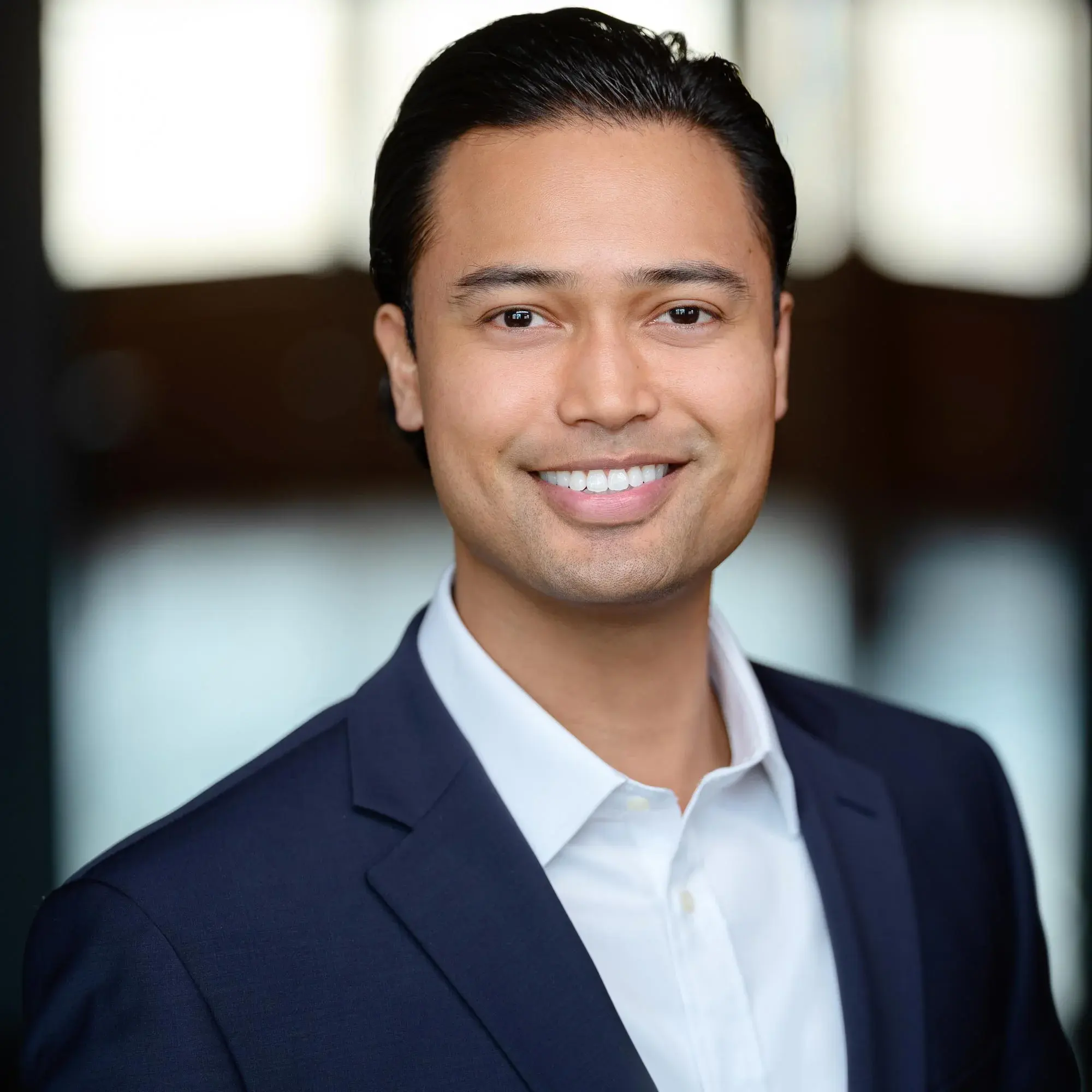 Professional headshot of a young, hip, and attractive businessman in a stylish suit, ideal for a LinkedIn profile